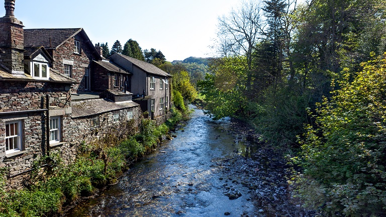 Riverside houses overlooking the river and trees in the beautiful Lake District town of Grasmere, one of the National Park's most sought-after destinations